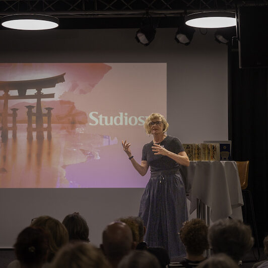 Studiosus-Referentin auf der Bühne vor Titelbild der Präsentation zum Thema Japan